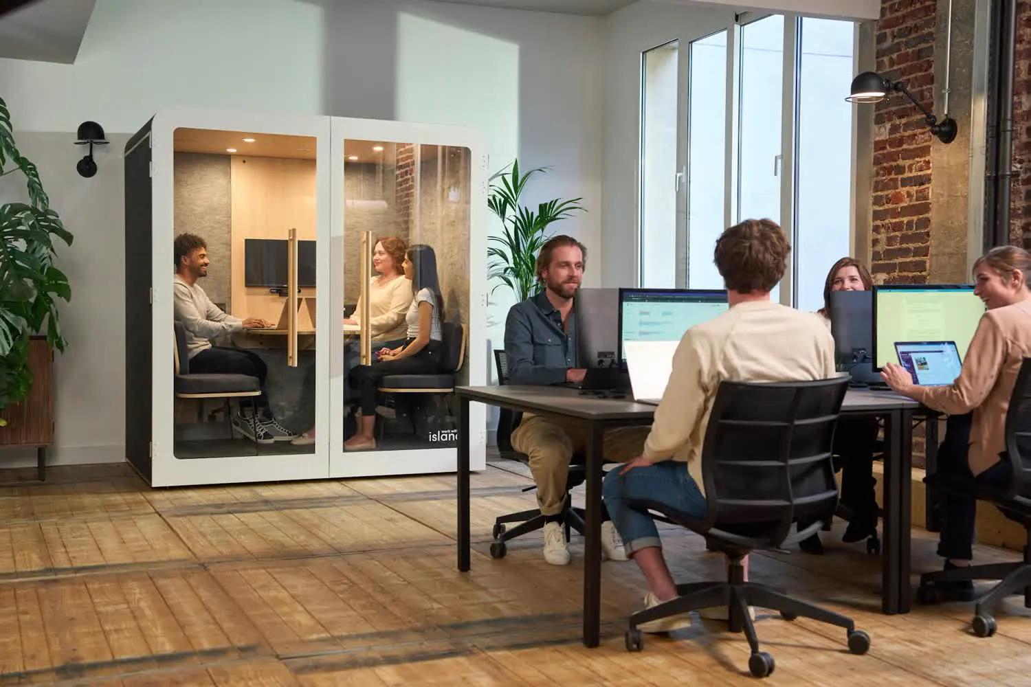 An office with candidates being interviewed in glass booths while a team reviews results on screens